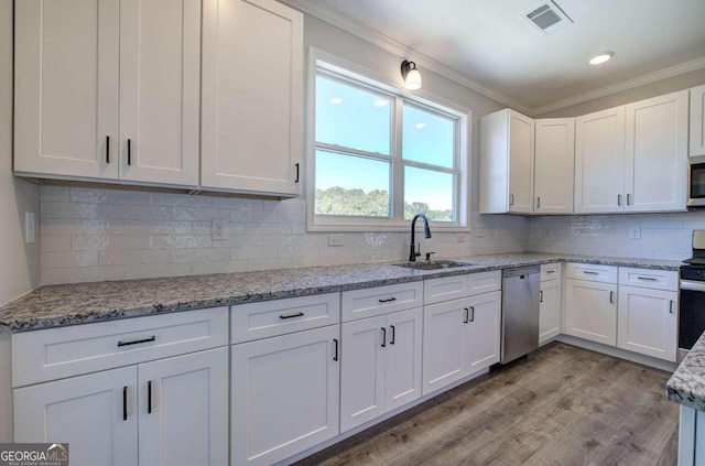 kitchen with appliances with stainless steel finishes, white cabinetry, sink, and light hardwood / wood-style floors