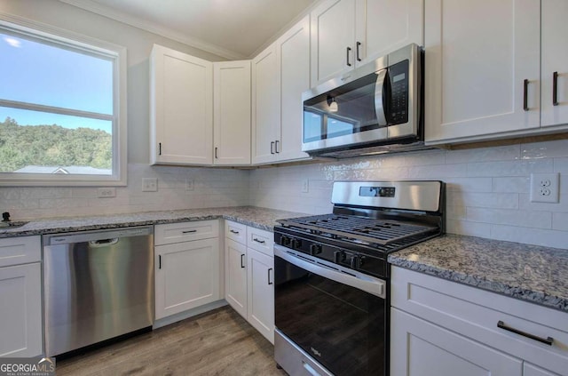 kitchen featuring appliances with stainless steel finishes, light hardwood / wood-style flooring, white cabinets, and light stone countertops