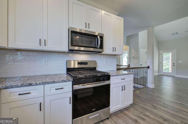 kitchen with light stone counters, appliances with stainless steel finishes, light wood-type flooring, and white cabinets