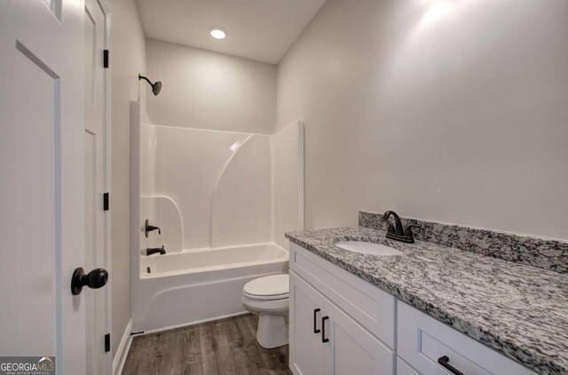 full bathroom featuring toilet, bathtub / shower combination, hardwood / wood-style floors, and vanity