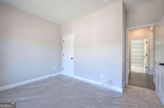 unfurnished bedroom with a closet, carpet flooring, and a spacious closet