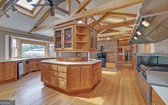 kitchen with a skylight, a center island, light wood-type flooring, and beamed ceiling