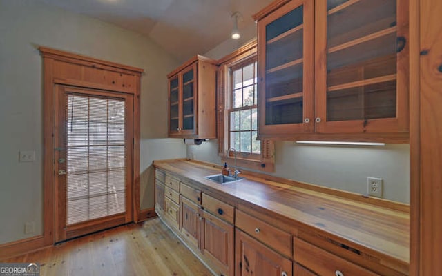 kitchen featuring lofted ceiling, sink, and light wood-type flooring