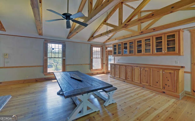 dining space with ceiling fan, light hardwood / wood-style flooring, and vaulted ceiling with beams