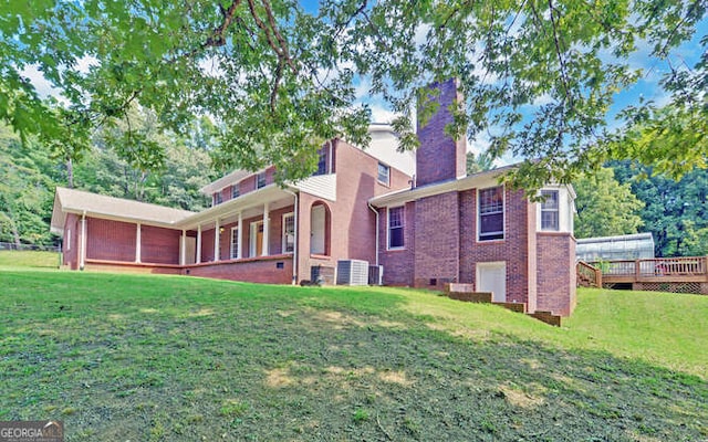 rear view of property with a wooden deck, cooling unit, and a lawn