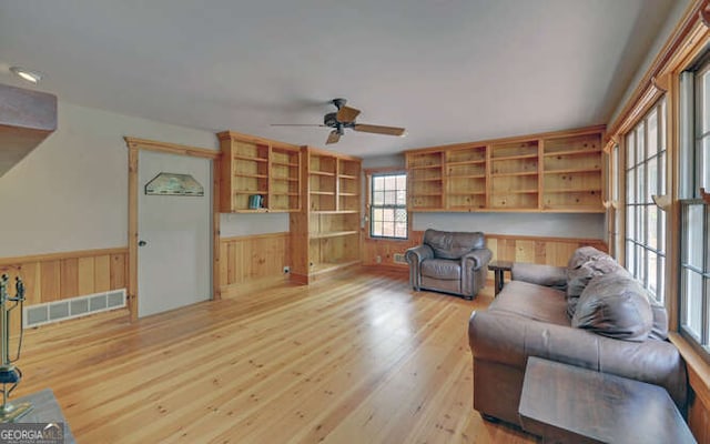 living room with wood walls, light hardwood / wood-style flooring, and ceiling fan