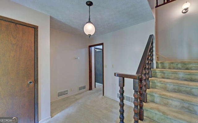 stairway featuring a textured ceiling and carpet