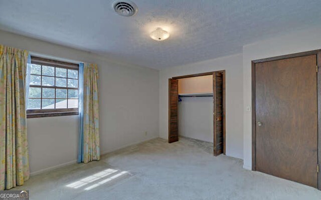 unfurnished bedroom featuring light carpet and a closet