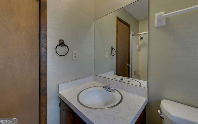 bathroom featuring vanity, walk in shower, and toilet