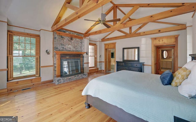 bedroom featuring beamed ceiling, a brick fireplace, wood-type flooring, and high vaulted ceiling