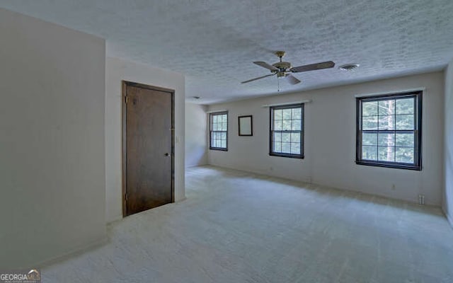 empty room with light carpet, a textured ceiling, and ceiling fan