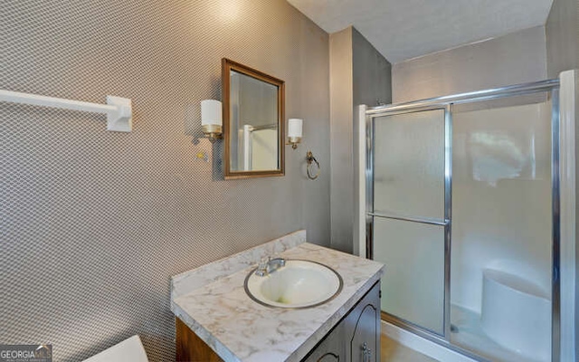 bathroom featuring vanity, toilet, and a shower with shower door