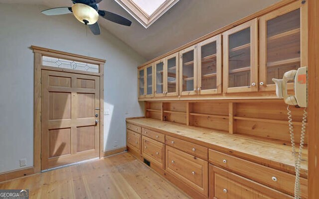 entryway with lofted ceiling with skylight, light wood-type flooring, and ceiling fan