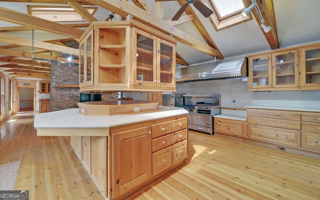 kitchen with light wood-type flooring, a center island, a kitchen breakfast bar, ceiling fan, and lofted ceiling with skylight