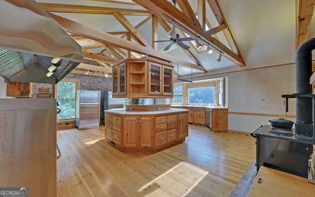 kitchen featuring island range hood, light hardwood / wood-style flooring, stainless steel fridge, high vaulted ceiling, and ceiling fan