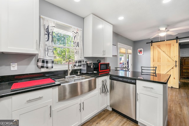 kitchen with dishwasher, a wealth of natural light, a barn door, and white cabinets