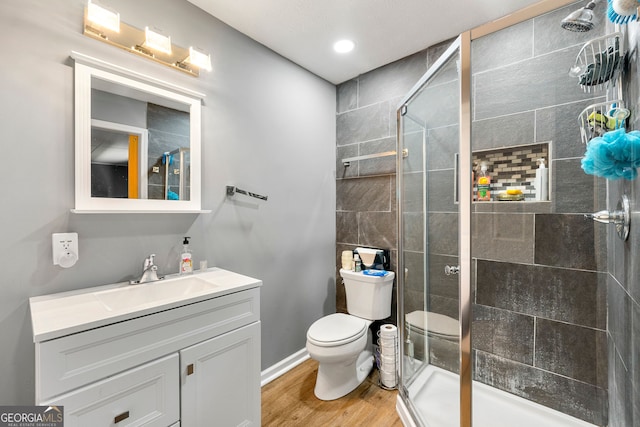 bathroom featuring vanity, hardwood / wood-style floors, a shower with shower door, and toilet