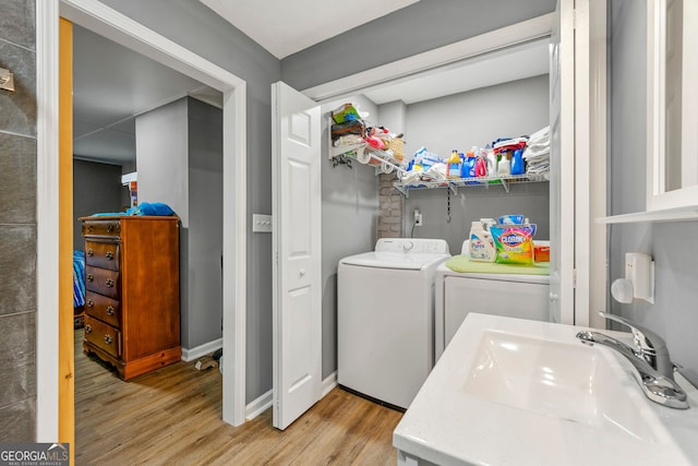 washroom featuring sink, light wood-type flooring, and washing machine and clothes dryer