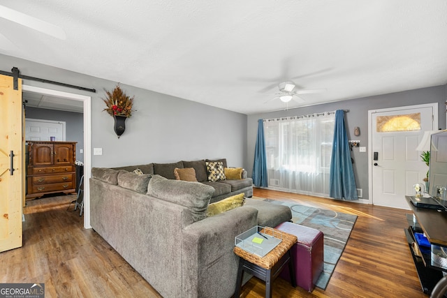 living room with hardwood / wood-style floors, a barn door, and ceiling fan