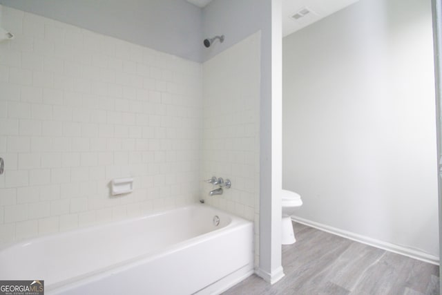 bathroom with toilet, tiled shower / bath, and hardwood / wood-style flooring