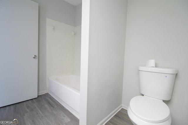 bathroom featuring toilet, tiled shower / bath combo, and hardwood / wood-style floors