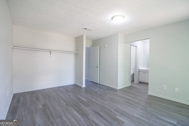 unfurnished bedroom with ensuite bathroom, dark hardwood / wood-style floors, and a closet