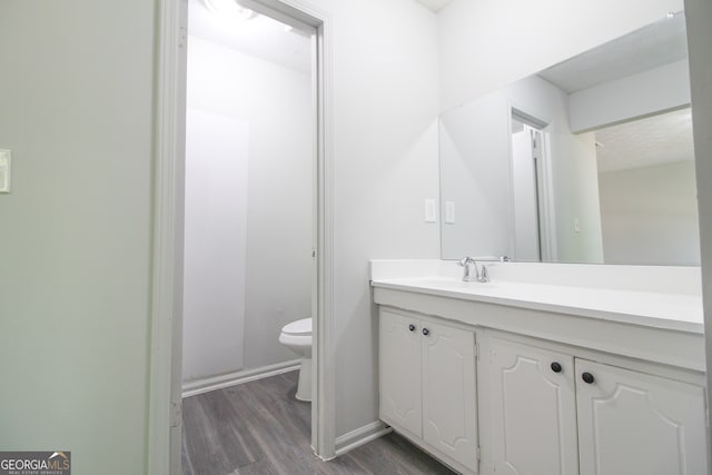 bathroom with toilet, hardwood / wood-style flooring, and vanity