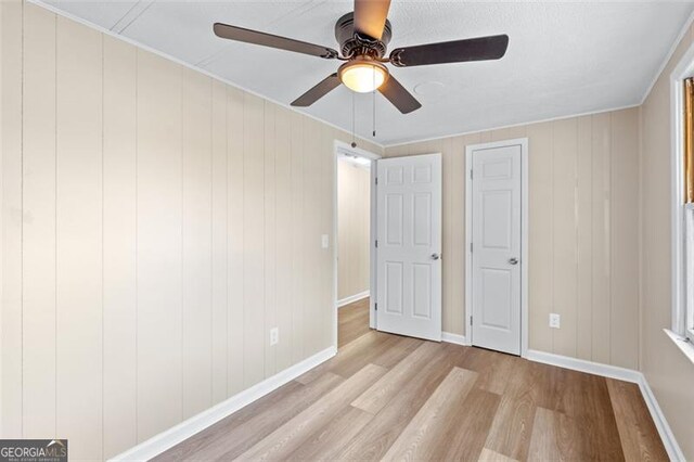 unfurnished bedroom with a ceiling fan, wood finished floors, and baseboards