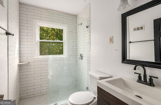 bathroom with toilet, vanity, and a tile shower