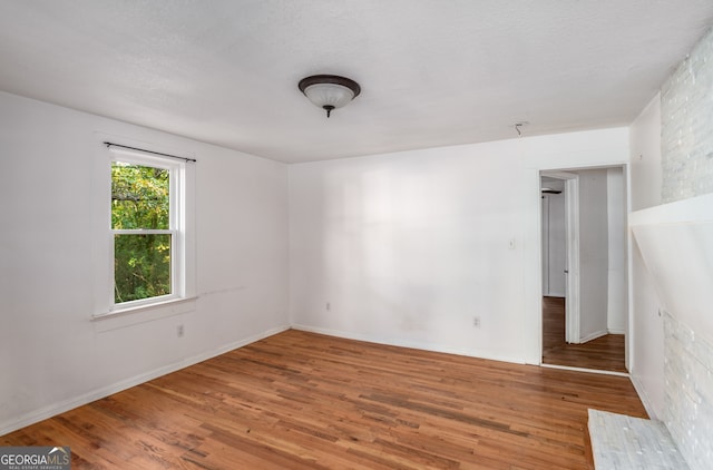 spare room featuring wood-type flooring and a textured ceiling