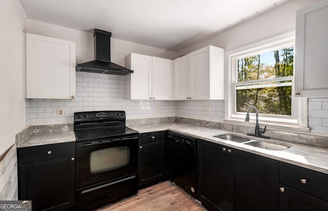 kitchen with wall chimney range hood, light hardwood / wood-style flooring, sink, black appliances, and white cabinetry