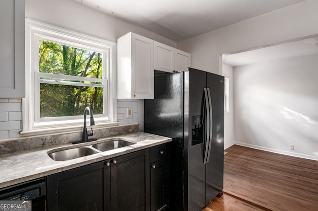 kitchen featuring black appliances, sink, backsplash, white cabinetry, and light hardwood / wood-style floors