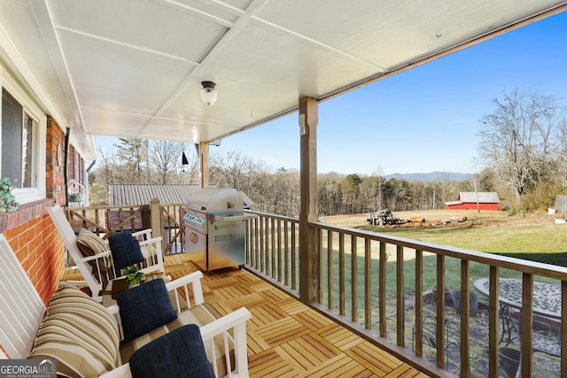 wooden terrace featuring a yard and a grill