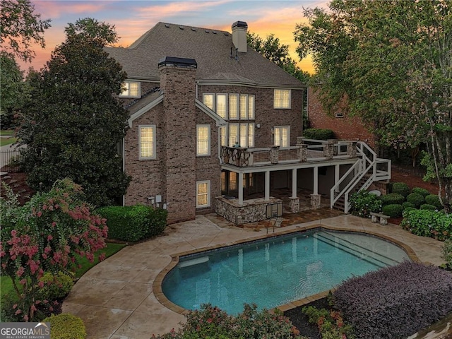 back house at dusk with a patio area and a pool side deck