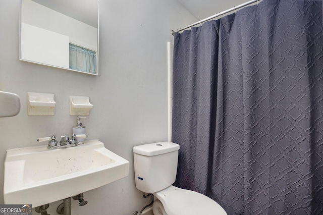 bathroom with toilet, sink, and a shower with curtain