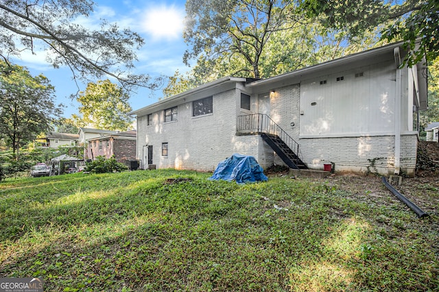 rear view of house featuring a yard and central AC unit