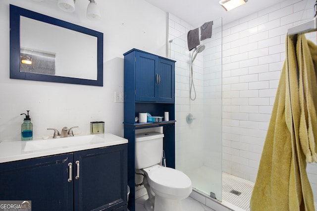 bathroom with vanity, toilet, a tile shower, and tile patterned flooring