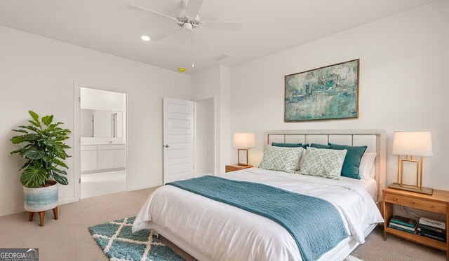 bedroom with ceiling fan, light carpet, and connected bathroom