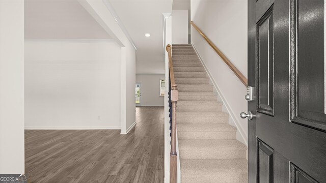 stairway with ornamental molding and hardwood / wood-style flooring