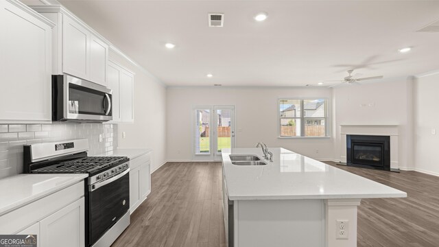 kitchen with a kitchen island with sink, white cabinetry, sink, and appliances with stainless steel finishes