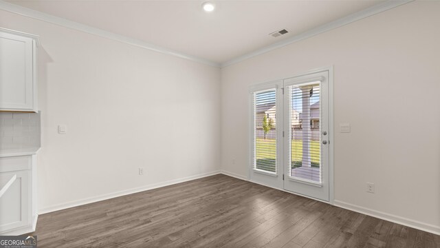 spare room with crown molding and dark wood-type flooring