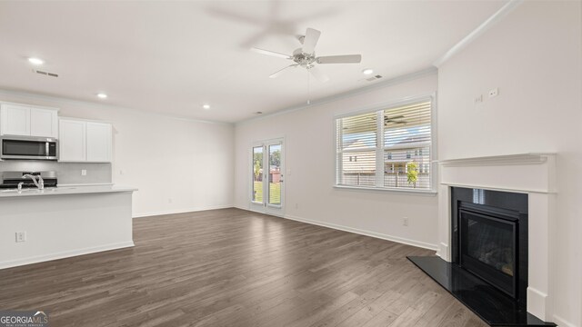 unfurnished living room with ceiling fan, crown molding, dark hardwood / wood-style floors, and sink