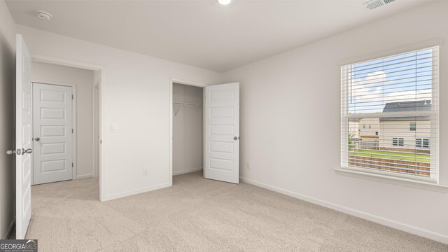 unfurnished bedroom featuring light carpet and a closet