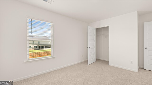 unfurnished bedroom with a closet and light colored carpet