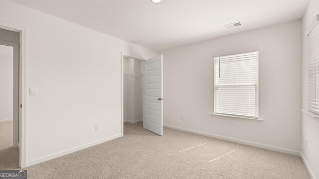 unfurnished bedroom featuring light colored carpet and a closet