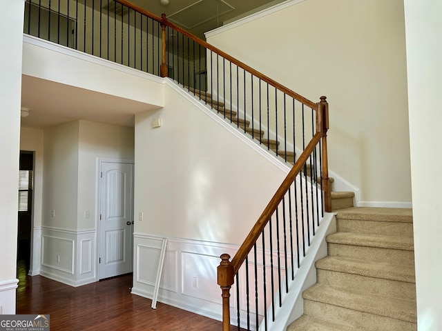 staircase with a towering ceiling and hardwood / wood-style floors