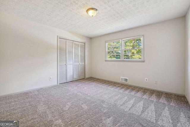 unfurnished bedroom with a closet, a textured ceiling, and carpet