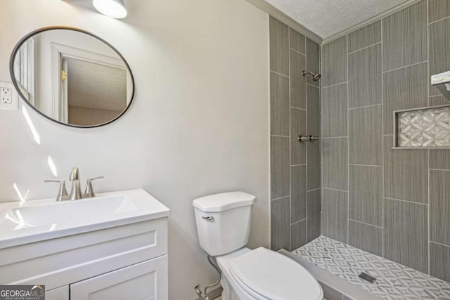 bathroom with toilet, a textured ceiling, vanity, and a tile shower