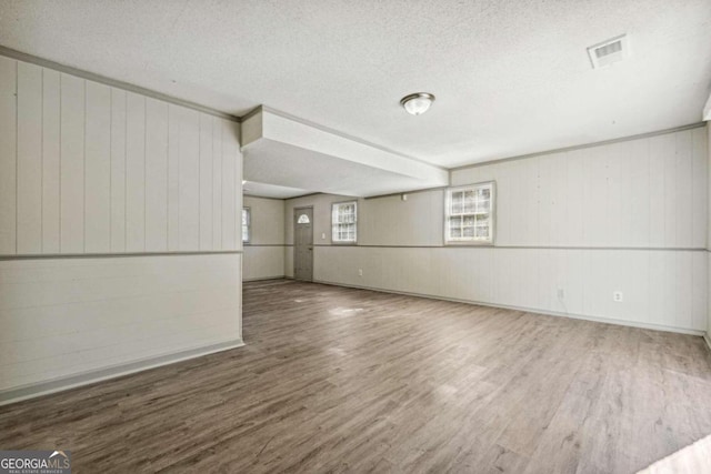 interior space with hardwood / wood-style floors, a textured ceiling, and wooden walls