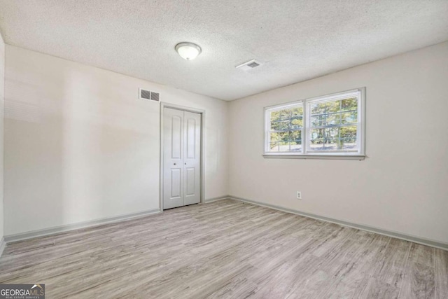 empty room with a textured ceiling and light wood-type flooring